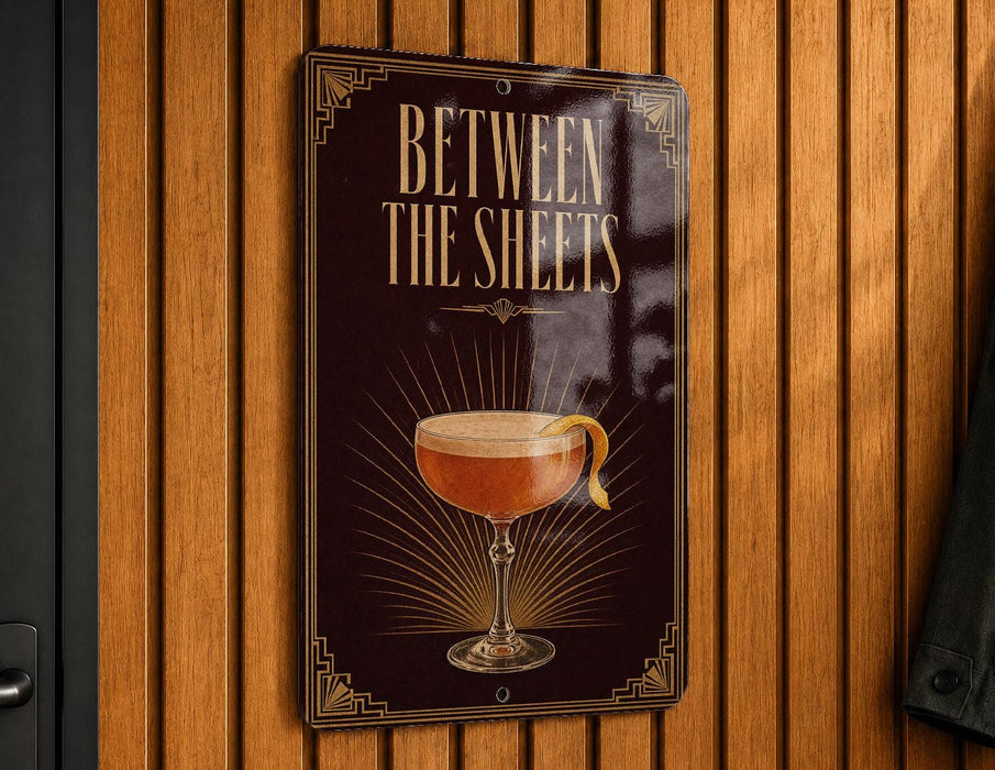 A sign with the text "Between the sheets" and an illustration of a cocktail glass with a lemon peel.