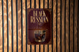 a sign with the text "Black Russian" and an illustration of a glass containing a dark liquid, likely a cocktail or a similar type of drink.