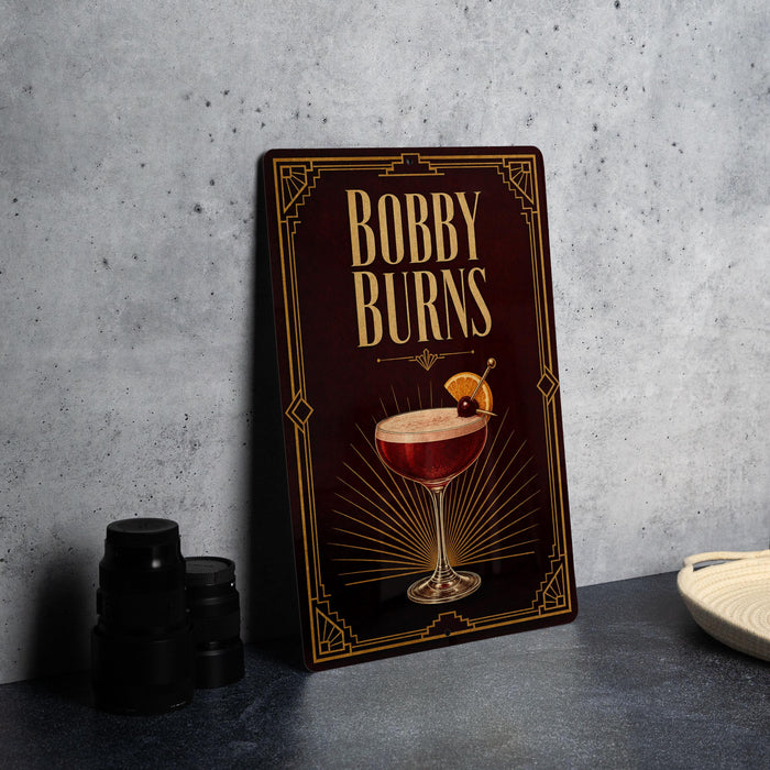 A decorative sign for "Bobby Burns" cocktail, featuring an illustration of a cocktail glass with a cherry and a decorative border.