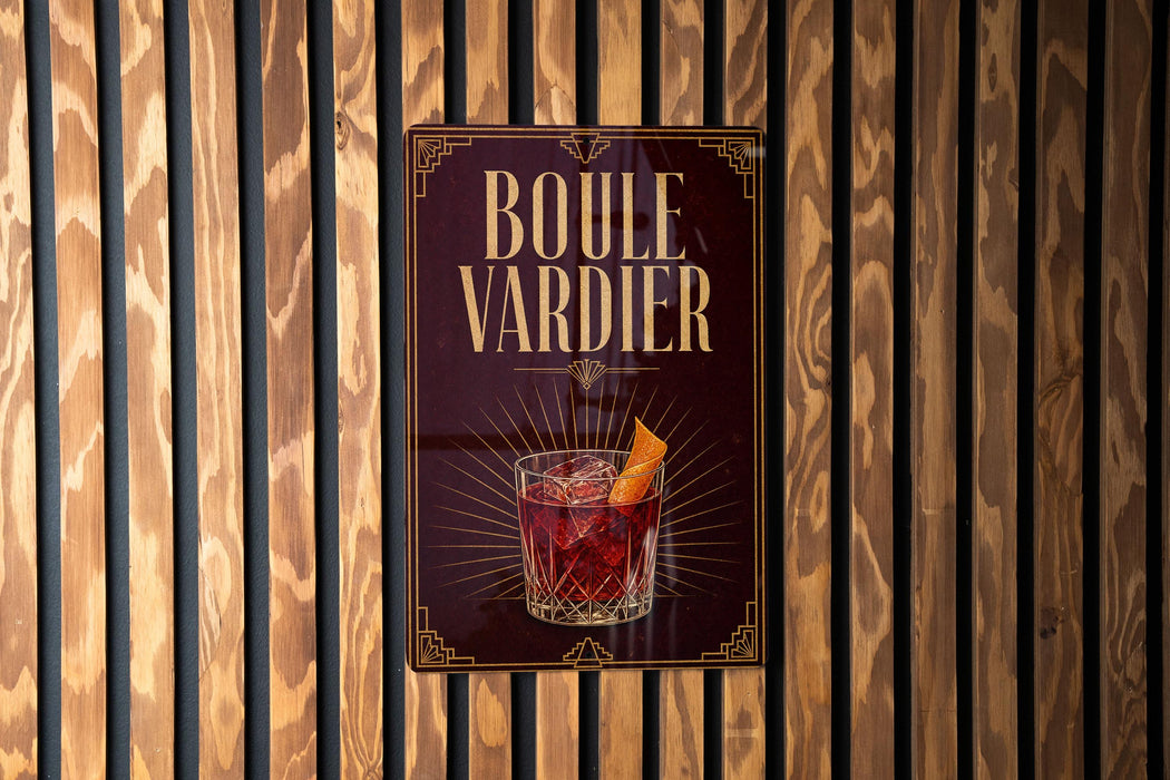 A sign with the text "BOULE VARDIER" and an illustration of a cocktail is displayed on a wooden wall.