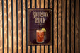 A sign for "Bourbon Buck", featuring an illustration of a glass of amber-colored liquid with a lime wedge.