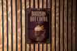 A sign for "Bourbon Hot Cocoa" is displayed on a wooden wall.