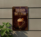 A sign advertising "BOURBON HOT COCOA" is displayed on a wall, featuring an illustration of a hot chocolate drink with whipped cream and a slice of orange.