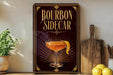 A decorative sign for a bourbon cocktail, featuring an illustration of a cocktail glass with a lemon peel, placed on a wooden surface next to a cutting board and some lemons.