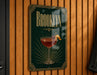 A sign for "Brooklyn" cocktail, featuring a glass of red wine with a cherry on top, is displayed on a wooden wall.