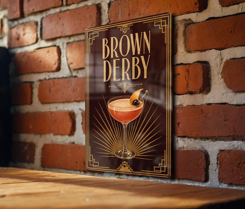 A framed poster of a cocktail called "Brown Derby" is displayed on a brick wall.