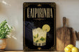 a decorative sign for a Caipiruna cocktail, with a glass of the drink and a lemon slice on the sign.