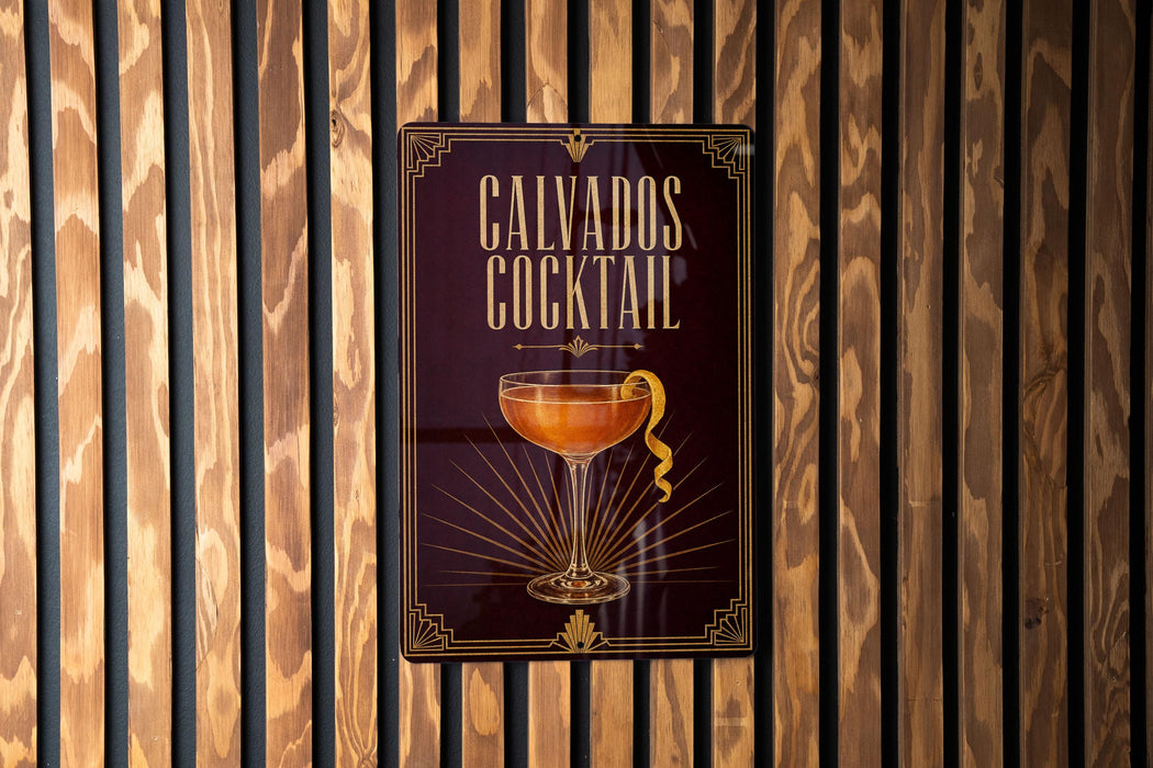 A sign for a cocktail called "Calvados Cocktail" is displayed on a wooden wall.