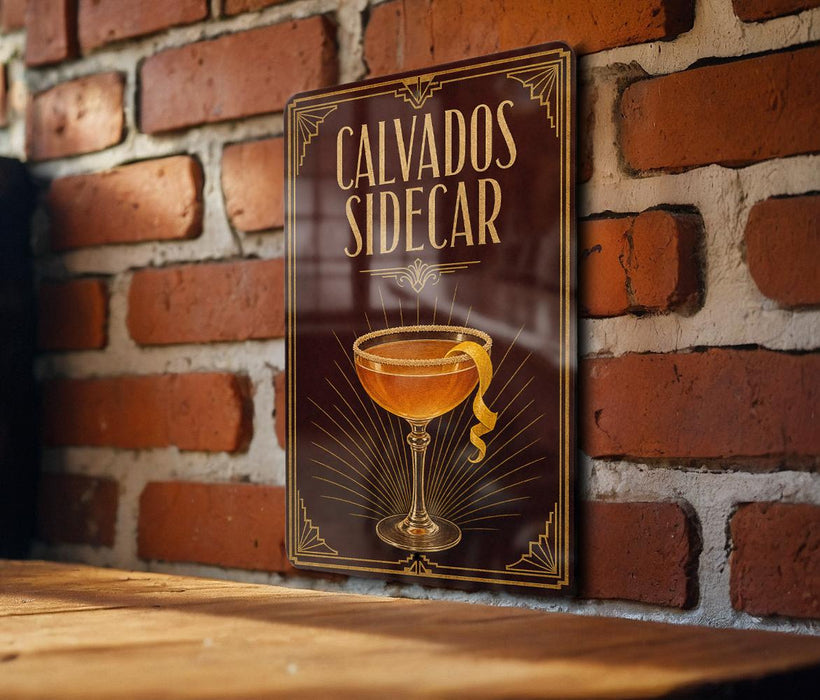 A sign with the text "CALVADOS SIDECAR" and an illustration of a cocktail glass with a lemon peel on a wooden surface against a brick wall.