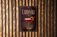 A sign for "Cardinale" cocktail is displayed on a wooden wall.