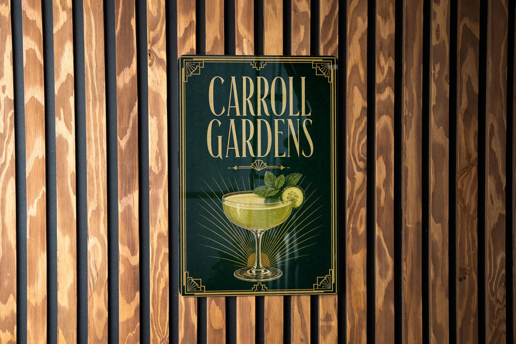 A sign for Carroll Gardens, featuring a cocktail glass with a lime garnish, is displayed on a wooden wall.