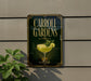 A sign for Carroll Gardens, featuring a cocktail glass with a lemon slice and mint garnish, mounted on a wall next to a plant.