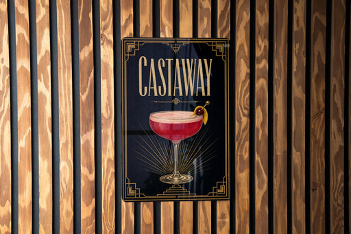A poster with the word "CASTAWAY" and an illustration of a cocktail on a wooden wall.
