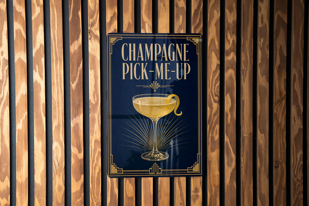A sign with the text "CHAMPAGNE PICK-ME-UP" and an illustration of a champagne glass with a lemon twist.