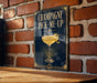 A sign with the text "CHAMPAGNE PICK-ME-UP" and an illustration of a champagne glass with a lemon twist.