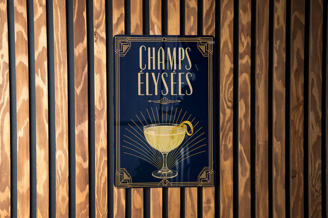 A sign with the text "CHAMPS ELYSEES" and an illustration of a cocktail glass with a lemon peel.