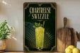 A framed poster advertising a Chartreuse Swzzle cocktail, featuring a glass of the drink with a mint leaf garnish.