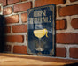 A sign with the text "CORPSE REVIVER NO. 2" and an illustration of a cocktail glass with a lemon peel.