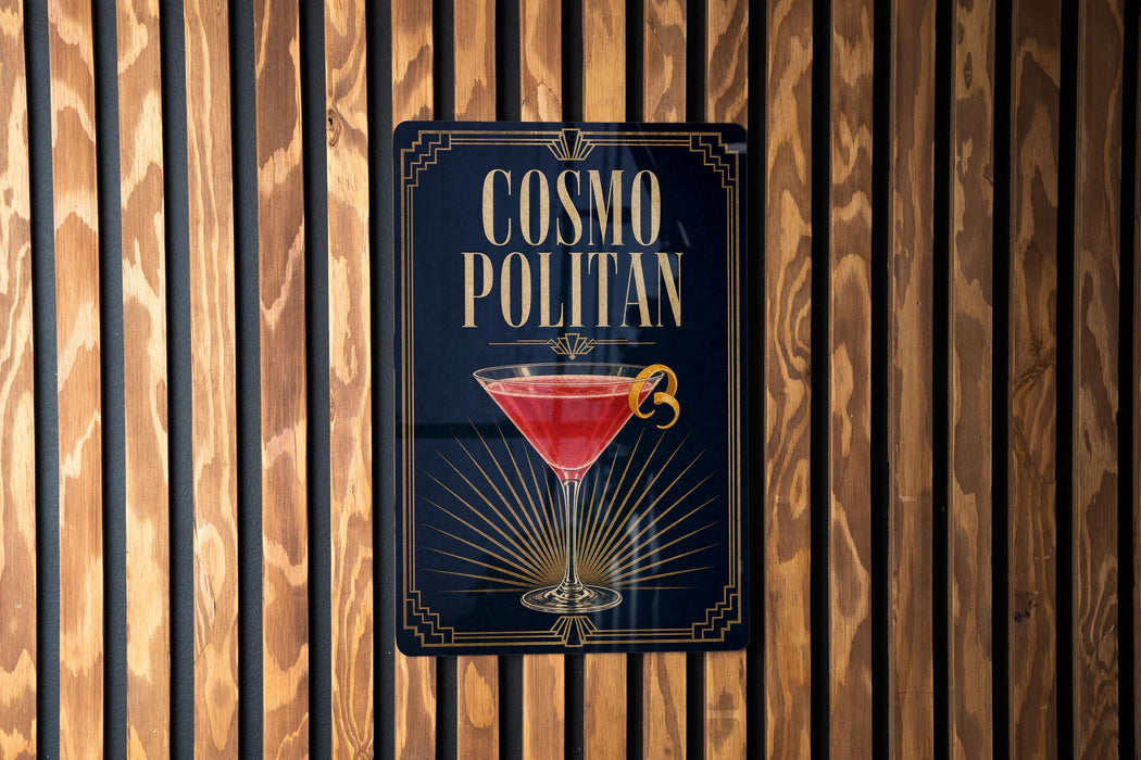A sign for a cocktail called "Cosmo Politan" is displayed on a wooden wall.