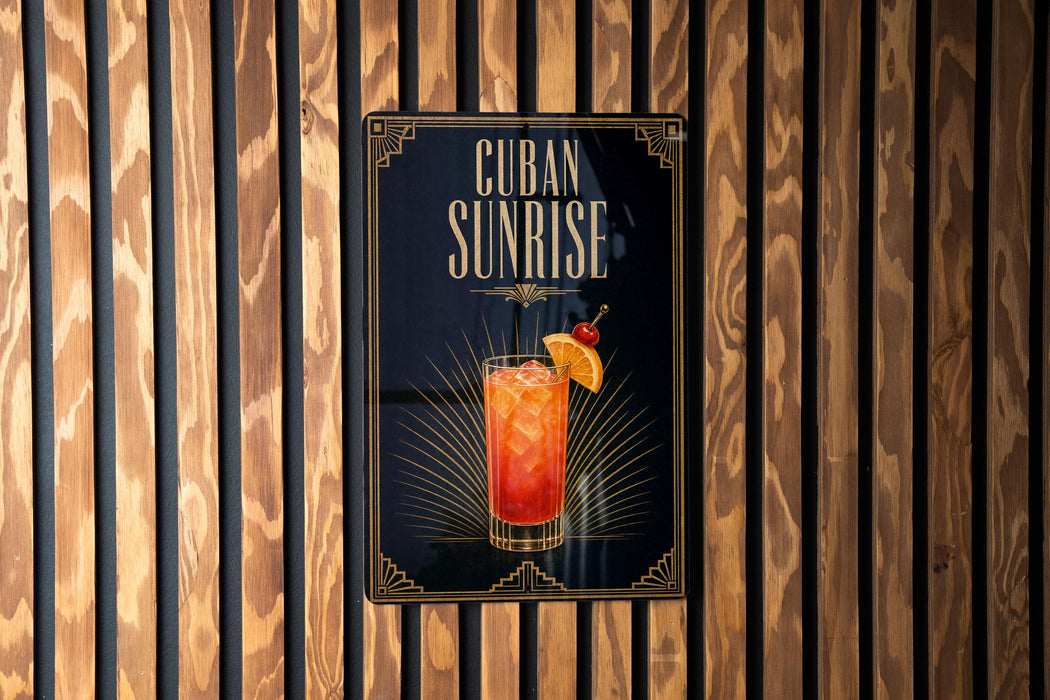 A sign for "Cuba Sunrise" cocktail, featuring an illustration of a colorful drink with a garnish and a straw.