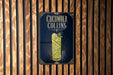 A sign for a cucumber Collins cocktail is displayed on a wooden wall.
