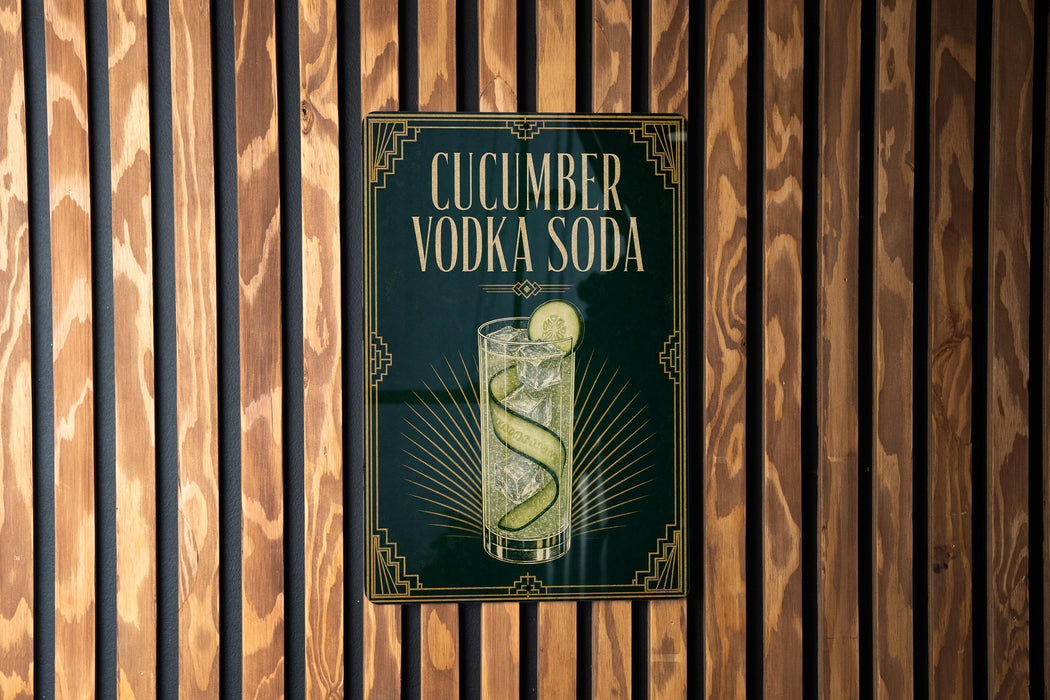 a sign for cucumber vodka soda, which is displayed on a wooden wall.