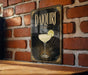 A decorative sign featuring a cocktail glass with a lemon slice, mounted on a brick wall.