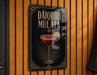 A sign for a drink called "Daiquiri Mulata" is displayed on a wooden wall.