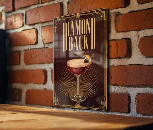 A sign with the text "DIAMOND BACK" and an illustration of a cocktail glass with a lemon on top, mounted on a brick wall.