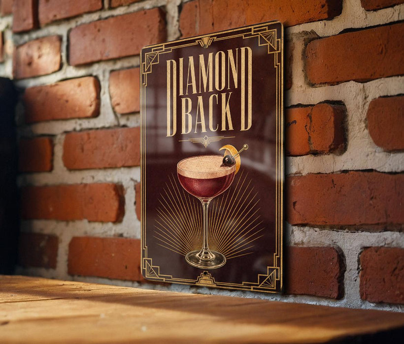 A sign with the text "DIAMOND BACK" and an illustration of a cocktail glass with a lemon on top, mounted on a brick wall.