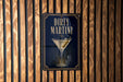 a sign for "Dirty Martini" with a martini glass illustration on a dark background.
