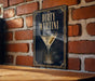 A framed poster of a martini glass with olives is displayed on a brick wall.