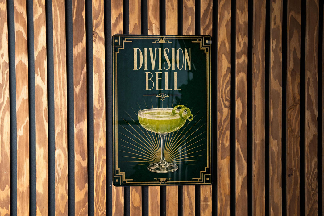 A sign for "Division Bell" cocktail is displayed on a wooden wall.
