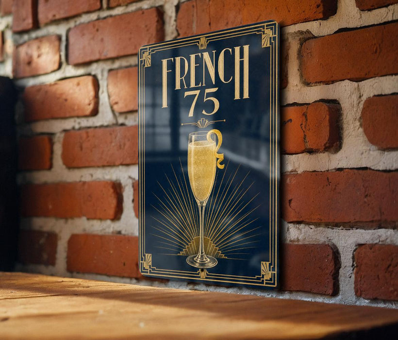 A framed poster with the text "FRENCH 75" and an illustration of a champagne glass is displayed on a brick wall.