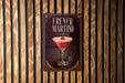 A poster advertising a French Martini is displayed on a wooden wall.