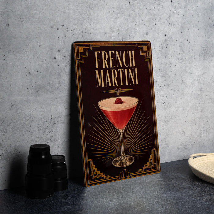 A framed image of a French martini cocktail is displayed on a wall, with a stack of black camera lenses and a white dish visible to the side.