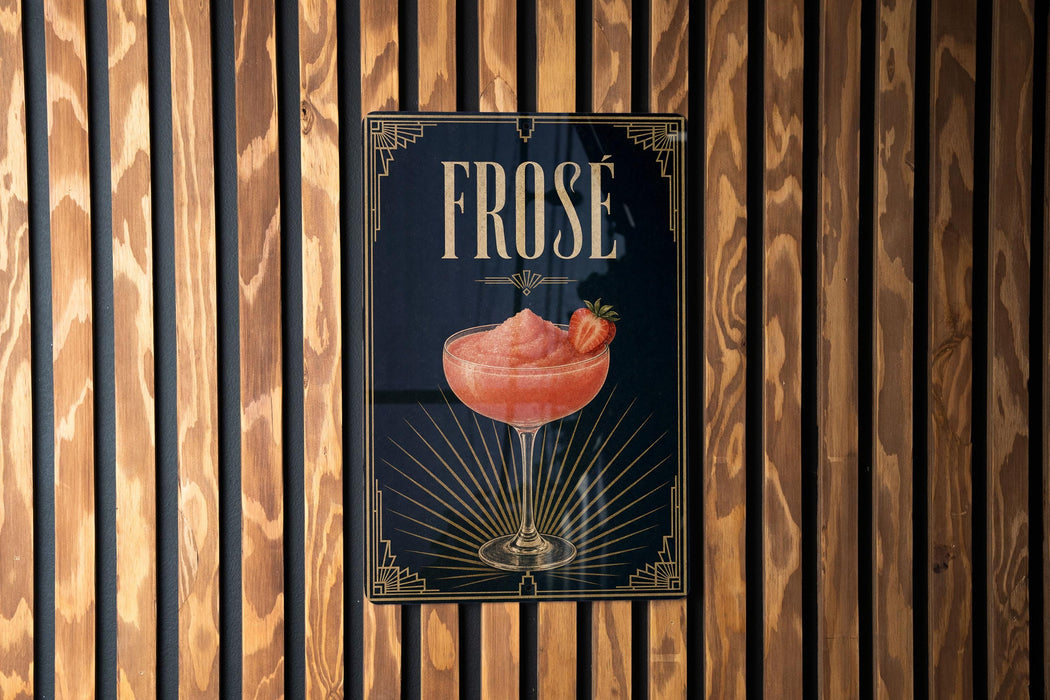 A poster with the word "FROSE" prominently displayed, featuring a glass of pink cocktail with a strawberry garnish.