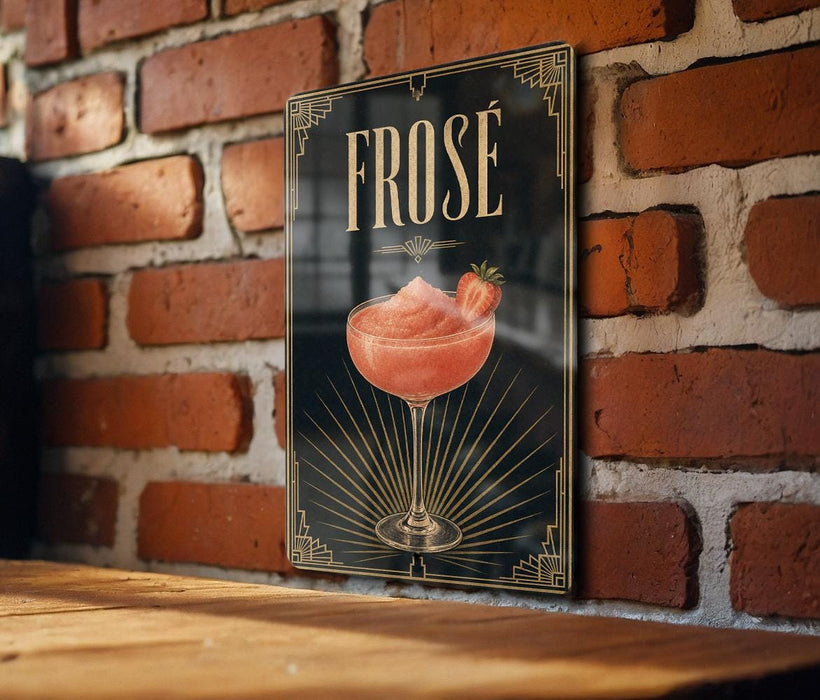 a framed poster of a pink cocktail glass with a strawberry garnish, mounted on a brick wall.