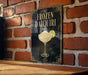 A sign for a frozen daiquiri cocktail is displayed on a brick wall.