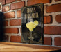 A framed poster of a frozen margarita is displayed on a brick wall, featuring a stylized illustration of a margarita glass with a lime wedge.
