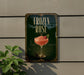 A sign for a frozen rose cocktail is displayed on a wall, with a plant visible to the left.