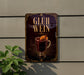 A sign with the text "GLÜH WEIN" and an illustration of a mug of hot chocolate with a slice of orange on top, mounted on a wall.