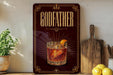 A framed advertisement for a drink called "Goddess" featuring a glass of amber-colored liquid with an orange slice garnish.