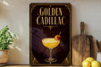 A decorative sign for a "Golden Cadillac" cocktail, featuring an illustration of a cocktail glass with a garnish and a lemon slice.