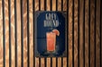 A poster advertising a drink called "Greyhound" is displayed on a wooden wall.