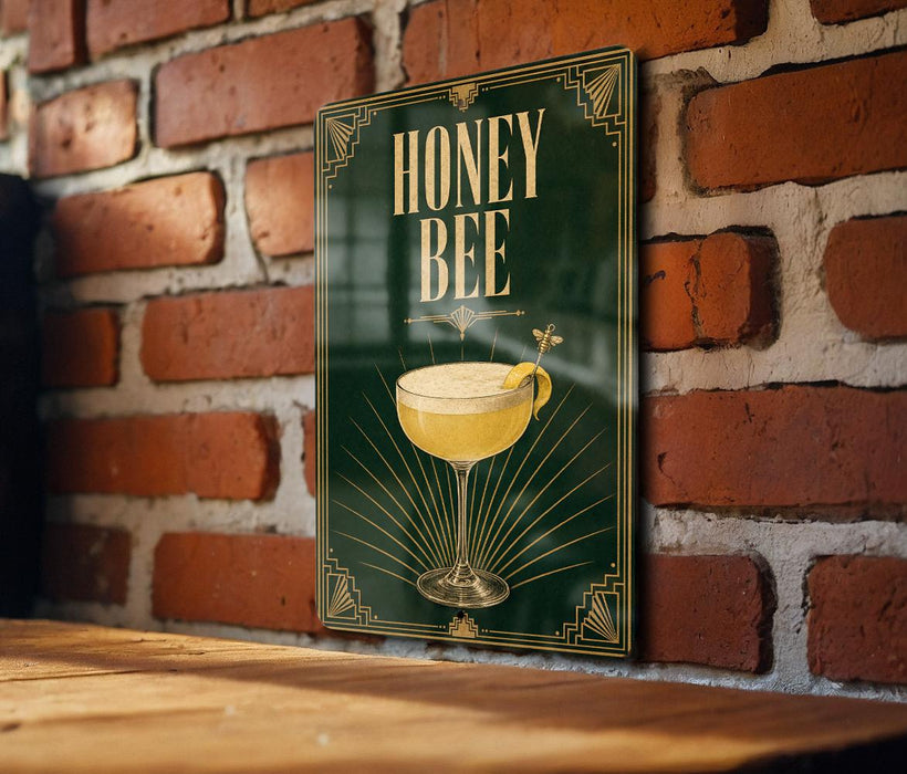 A poster with the text "HONEY BEE" and an illustration of a cocktail glass with a bee on top, hanging on a brick wall.