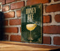 A poster with the text "HONEY BEE" and an illustration of a cocktail glass with a bee on top, hanging on a brick wall.