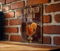 A sign for "Hot Spiced Cider" is displayed on a brick wall, featuring an illustration of a glass of hot cider with a slice of orange.