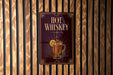 A sign with the text "HOT WHISKEY" and an illustration of a glass of whiskey with a lemon slice.