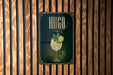 A poster for a drink called "HUGO" is displayed on a wooden wall.